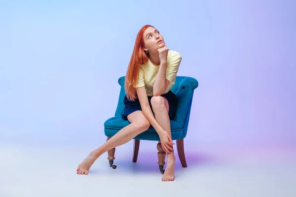 Chica pelirroja con hermosas piernas largas sentada en una silla —  Fotos de Stock