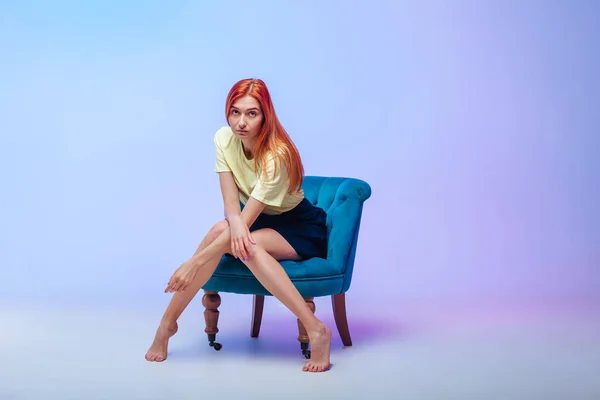 Röd-hårig flicka med vackra långa ben sitter på en stol — Stockfoto