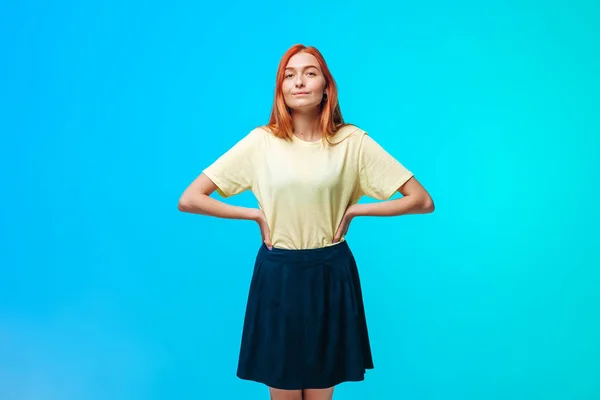 Chica pelirroja en una falda corta se levanta sobre un fondo azul-verde — Foto de Stock