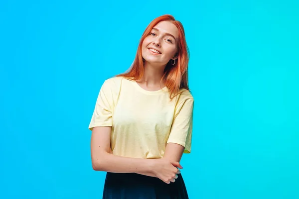 Chica pelirroja cruza los brazos y sonríe en una espalda azul-verde —  Fotos de Stock