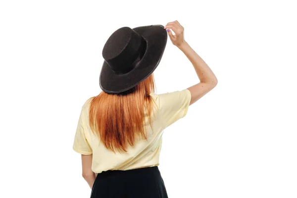 Pelirroja chica sosteniendo sombrero sobre fondo blanco aislar vista posterior —  Fotos de Stock