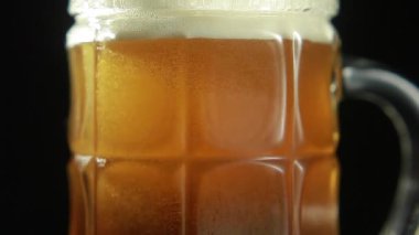 Bira, siyah arka plandaki bir bardağa dökülür. Yakın plan.