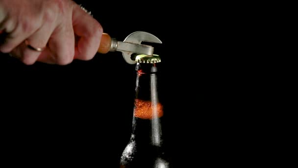 La mano abre un abrebotellas de cerveza sobre un fondo negro — Vídeo de stock