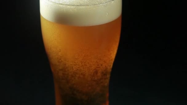 A sört egy fekete hátterű pohárba öntik, közelről. — Stock videók