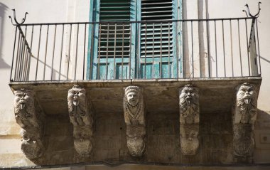 İtalya, Sicilya, Noto 'daki Nicolaci Sarayı' nın son barok tarzı balkonunda.