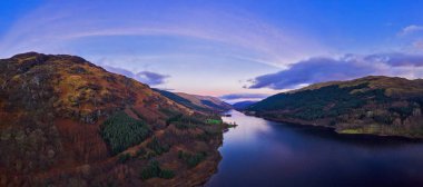 Scottish beautiful colorful sunset landscape with Loch Voil, mountains and forest at Loch Lomond & The Trossachs National Park. Nature evening scenery in Scotland over the mountain lake. clipart