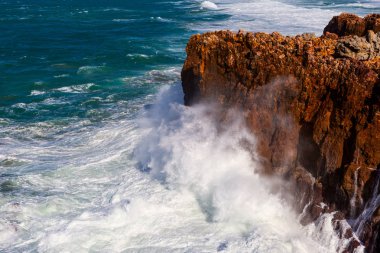 Sea waves hitting rocks cliff at Praia Da Bordeira, Portugal. clipart