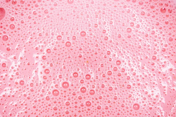 Strawberry milkshake texture. Pink bubbles of berry drink froth.Extreme close-up macro. Above view.