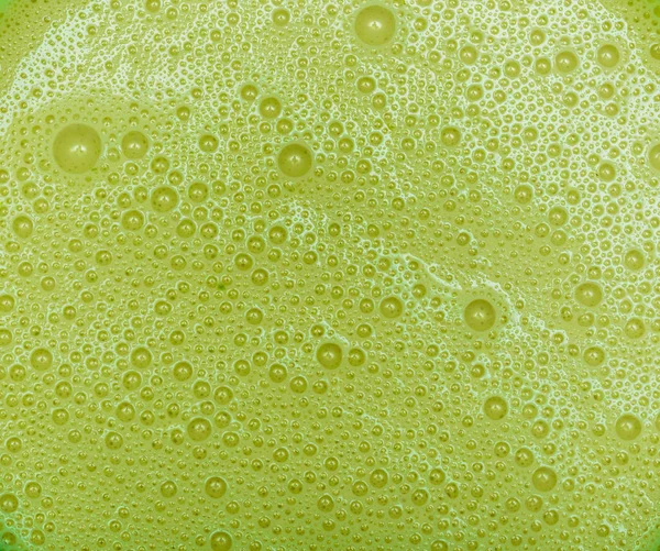 Avocado milkshake with texture. Green bubbles of drink froth. Extreme close-up macro. Above view. Healthy eating diet concept.