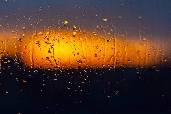 Fondo borroso al atardecer detrás de una ventana húmeda — Foto de Stock