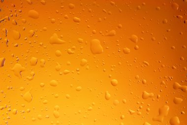 Sarı/oranage arka plan şeffaf cam üstünde su damlaları
