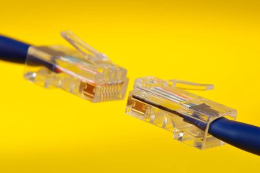 Two handing RJ-45 cables on yellow background clipart