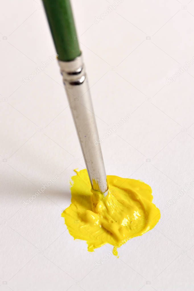 Brush mixing yellow paint on canvas