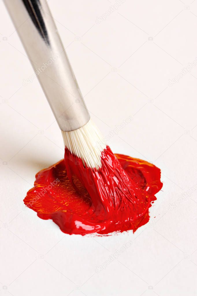 Brush mixing red paint on canvas