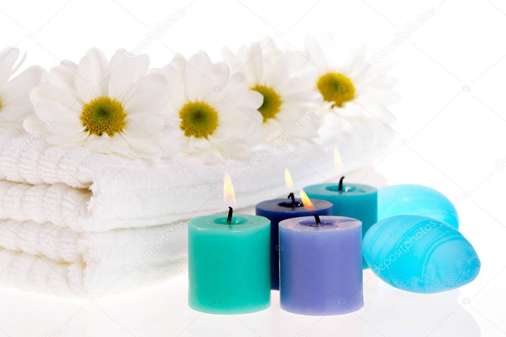 Towels, candles, and daisies on white isolated