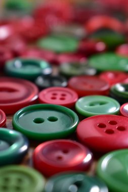 ahşap bir masa üzerinde yeşil ve kırmızı dikiş düğmeleri