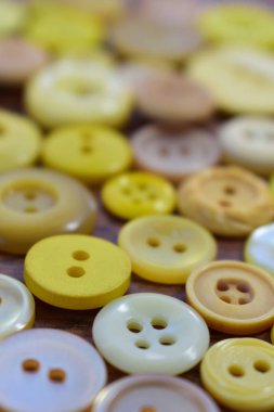 ahşap bir masa üzerindeki sarı dikiş düğmeleri