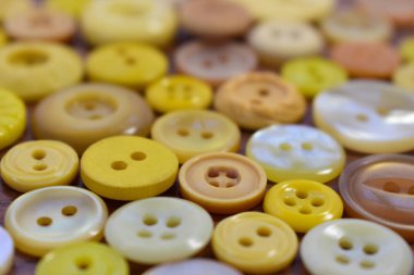 ahşap bir masa üzerindeki sarı dikiş düğmeleri