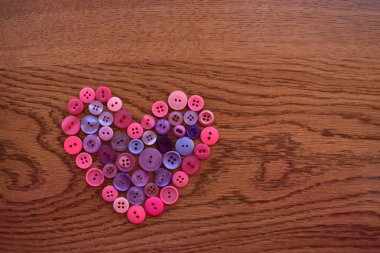 Mor ve pembe dikiş düğme kalp ahşap üzerine