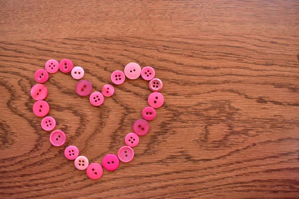 Mor ve pembe dikiş düğmeleri ahşap üzerine