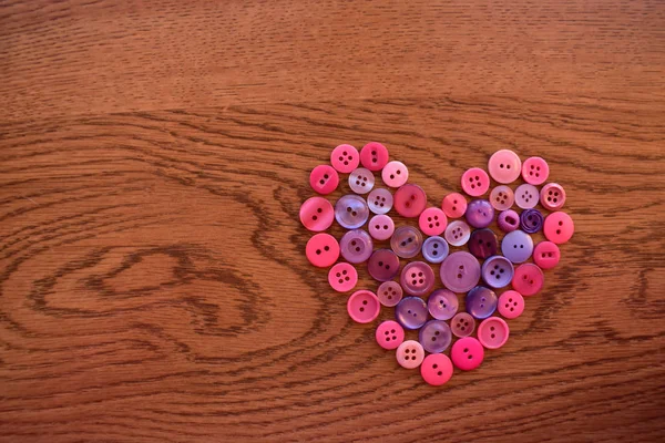 Mor ve pembe dikiş düğme kalp ahşap üzerine