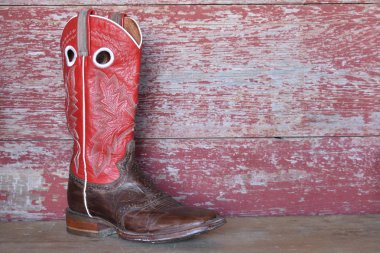 Kırmızı ahır tahta üzerinde kırmızı kovboy çizmesi