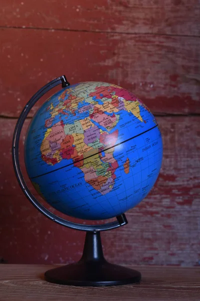 a world globe with a red barn board background