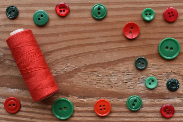 red thread and red and green sewing buttons on wood