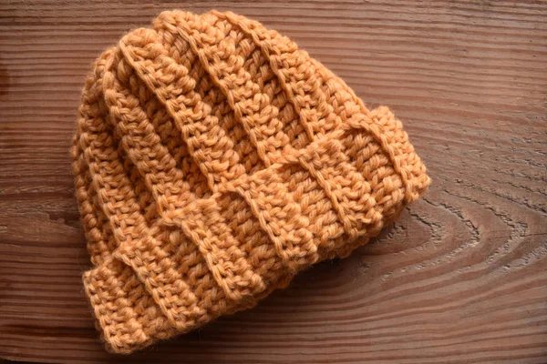 a horizontal of a tan crocheted hat isolated on wood
