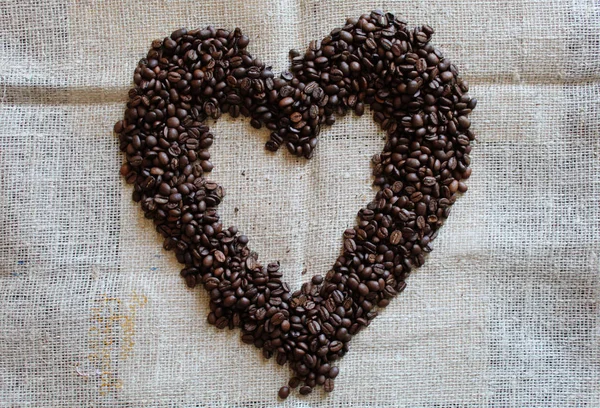 Heart of coffee beans on burlap. View from above. Brown colors.Loving coffee.