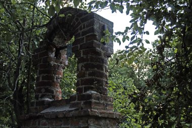 Eski kırmızı taştan yapılmış tarihi bir bina. Arka planda parktaki ağaçlar.