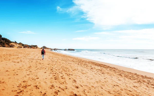 Okyanus kıyısında kumlu bir plaj boyunca yürüyüş bir sırt çantası ile kız gezgin