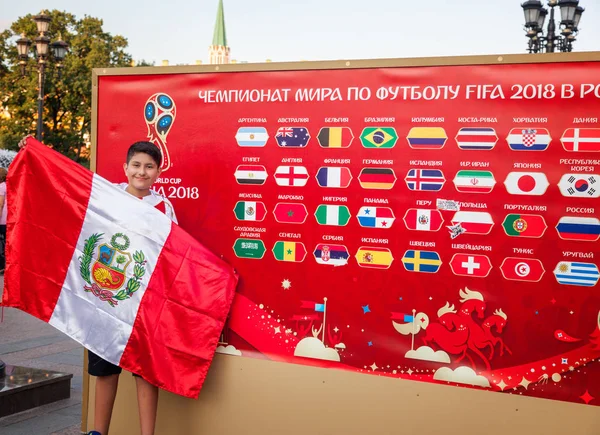 Moskova, Rusya. 18 Haziran 2018. Çocuk bir afiş arka plan Futbol Şampiyonası 2018 ülkeler üyeleri ile Perulu bir bayrağı ile genç bir kız