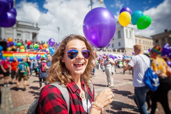 Beautiful young happy woman with a balloon, symbol of an LGBT community on a pride in a European city. Human Rights, Equality, LGBT, Freedom and Happiness