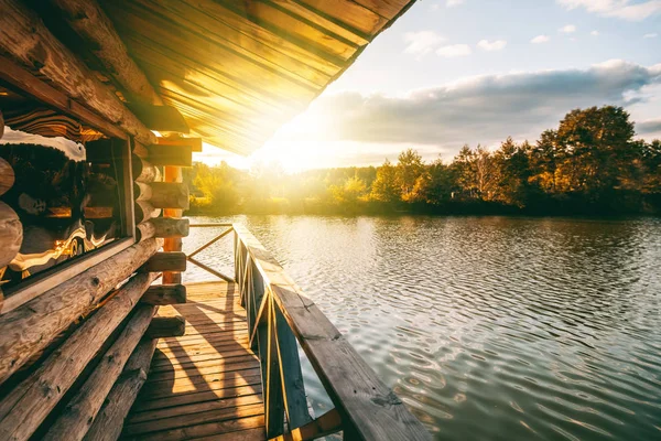 Casa de madera con una terraza sobre el agua en el lago, al atardecer