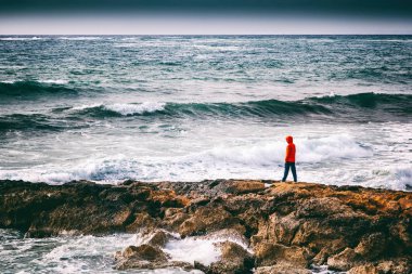Bir insan bir fırtına sırasında sahil üzerinde duruyor ve sahne, küçük bir adam ve büyük bir dünya, kavram hayran