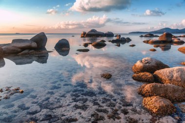 tropikal güzel manzara, büyük taşlar, sahilde günbatımı bulutlar suya yansıyan parlak