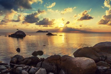 tropikal güzel manzara, büyük taşlar, sahilde günbatımı bulutlar suya yansıyan parlak