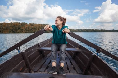 Güneşli bir günde bir ahşap tekne Gölde kürek kürek genç güzel kadın turist gezgin