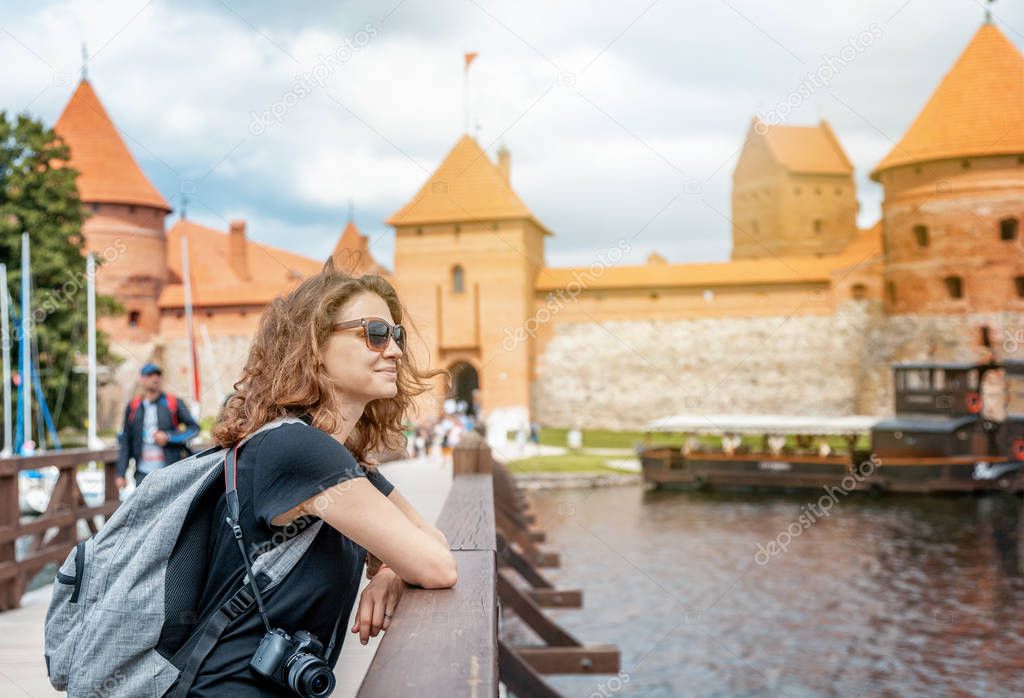 Beautiful young woman tourist traveler in the background Trakai castle on the lake, Lithuania sights, travel to the Baltic countries