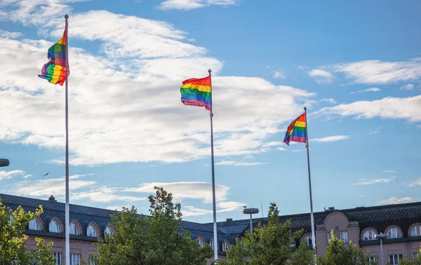 Rainbow flags on flagpoles fluttering in the wind against the blue sky in the city, a symbol of support and protection against discrimination of LGBT rights in Europe and developed countries