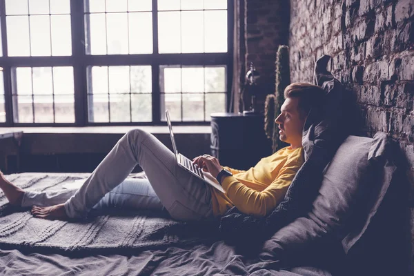 Молодий Чоловік Працює Ноутбуці Вдома Лежить Ліжку Фрілансер Цифровий Співробітник — стокове фото