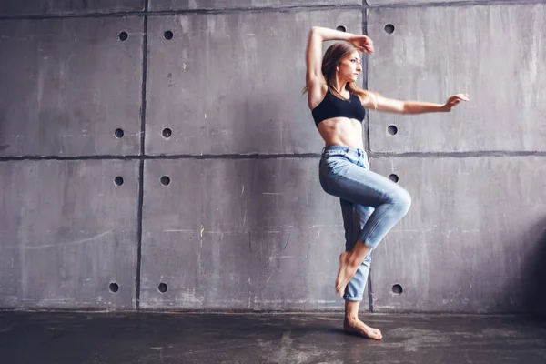 young beautiful woman in top and jeans dancing modern contemporary dance in the studio, contemporary art, harmony of body and soul, professional dancer