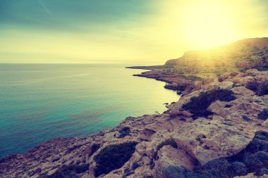 Parlak güzel gün batımı deniz kenarında çarpıcı. Kayalar ve gök masmavi bir deniz, Cape Greco, Kıbrıs