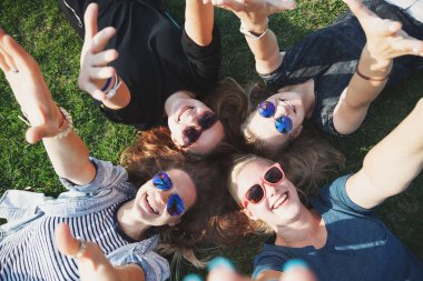 Park, millenial kavramı, gençlik ve öğrenci, turizm ve tatil çim üzerinde yalan mutlu gülümseyen kaygısız genç şık kız grubu