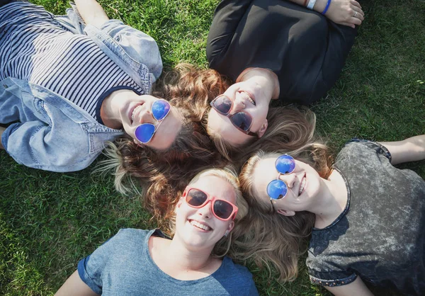 一群快乐的微笑无忧无虑的年轻时尚女孩躺在草地上的公园 千禧年概念 青年和学生 旅游和节假日 — 图库照片