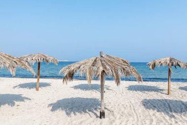 Güzel manzara, tropikal plaj beyaz kum ve palmiye yaprakları, şemsiyeleri ile sakin ve seyahat, minimalist kavramı