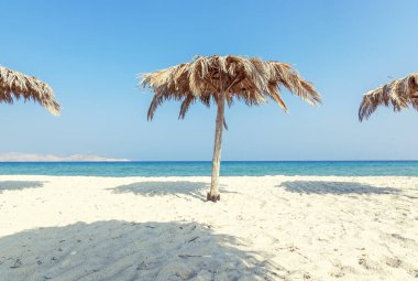 Güzel manzara, tropikal plaj beyaz kum ve palmiye yaprakları, şemsiyeleri ile sakin ve seyahat, minimalist kavramı