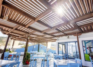 Plaj cafe ve restoran mavi ve beyaz masa ve sandalyeler güneş ışınlarının Yunan tarzı ile. Restoran İç