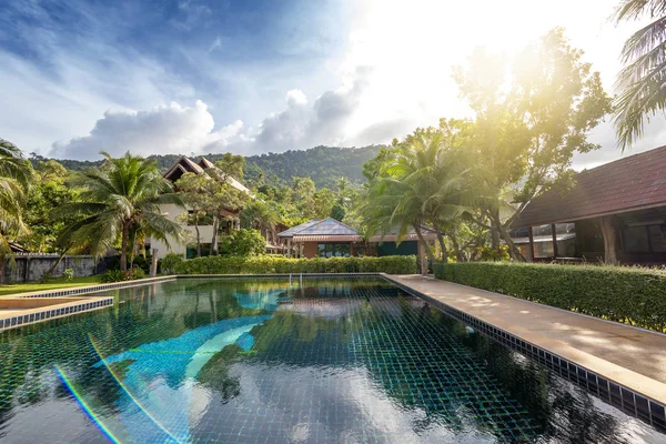 Bright tropical landscape, hotel pool overlooking the hills and palms, in the sun